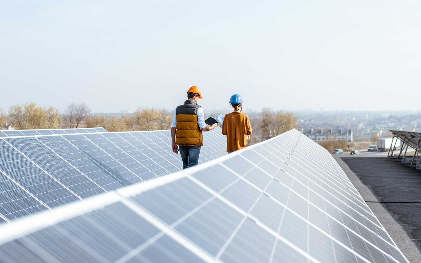 Employees walk between solar panels on a rooftop